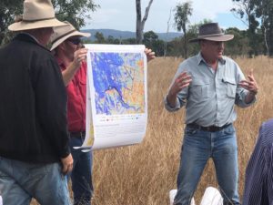 Two gentlemen hold up a multicoloured map as Grant Stone, Scientist, explains how to interpret it.