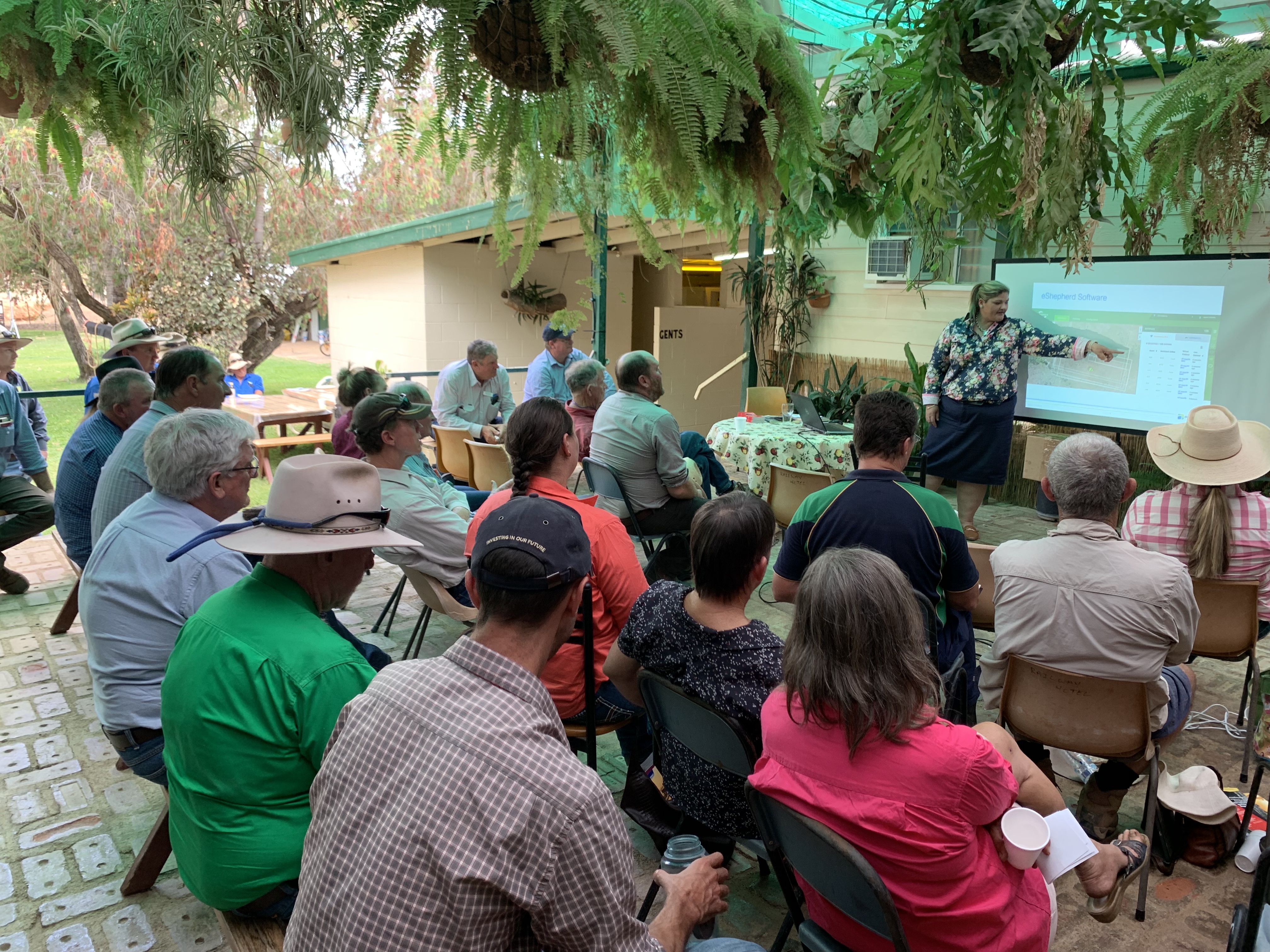 People sitting in chairs looking at a projector screen at a previous E-Beef meeting.