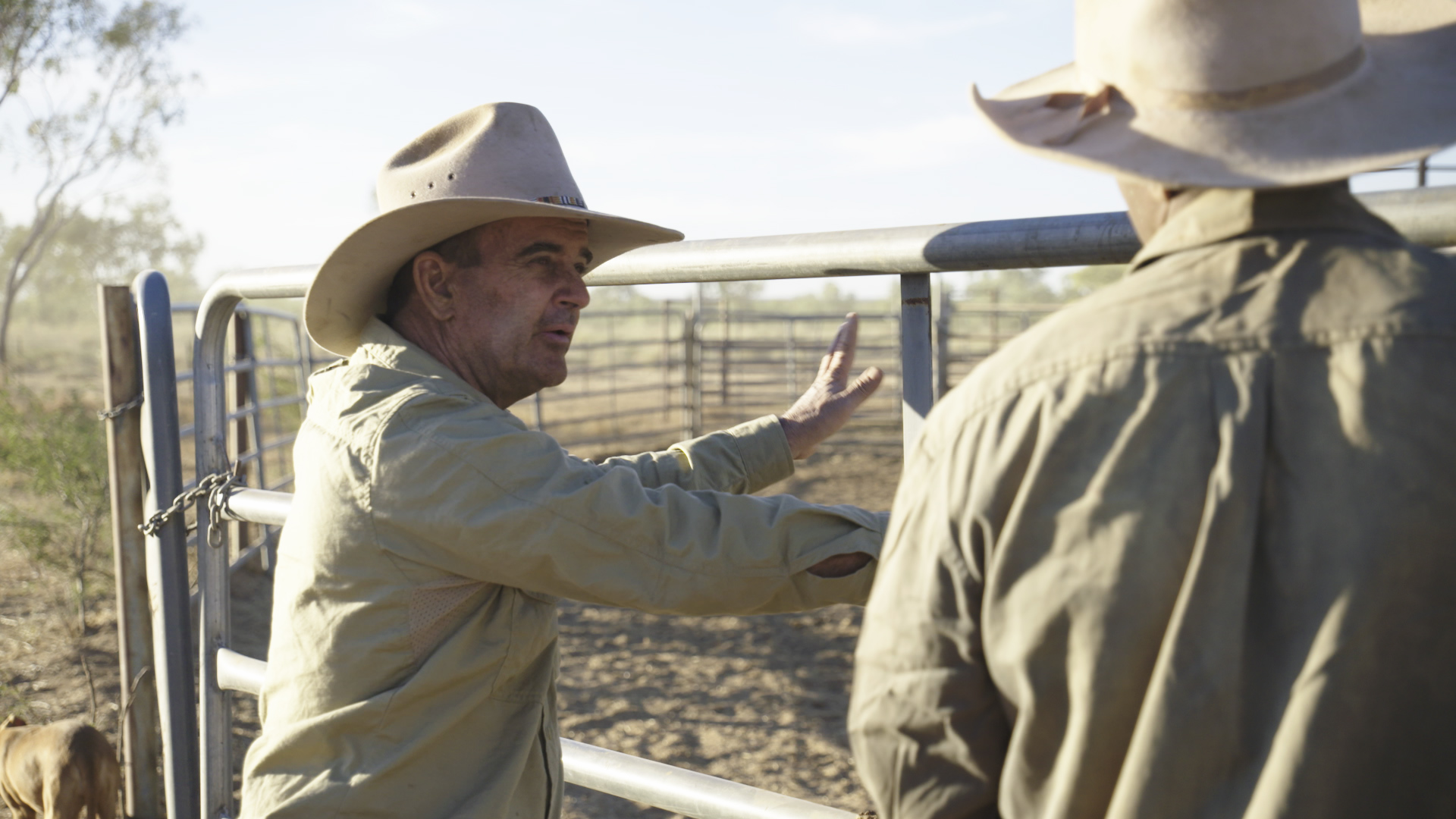 Man in a hat speaking to another man in a hat, leaning against portable panels.