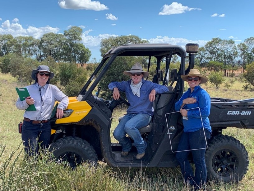 Three females in a paddock with a quadrat conducting botanal surveys