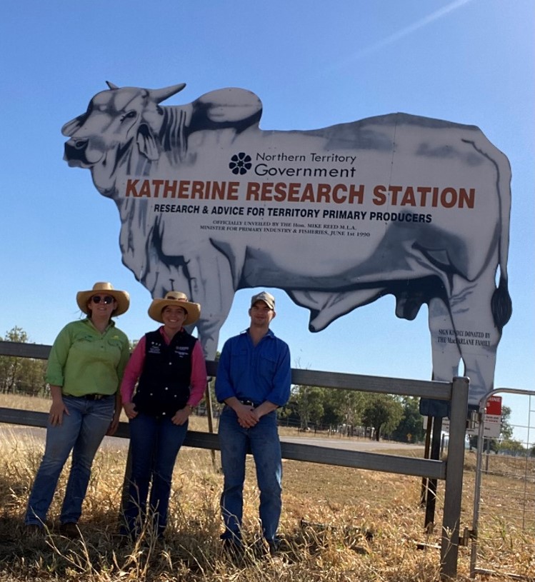 Beef extension officers stand in front of the iconic Katherine Research Station sign in the shape of a large Brahman bull