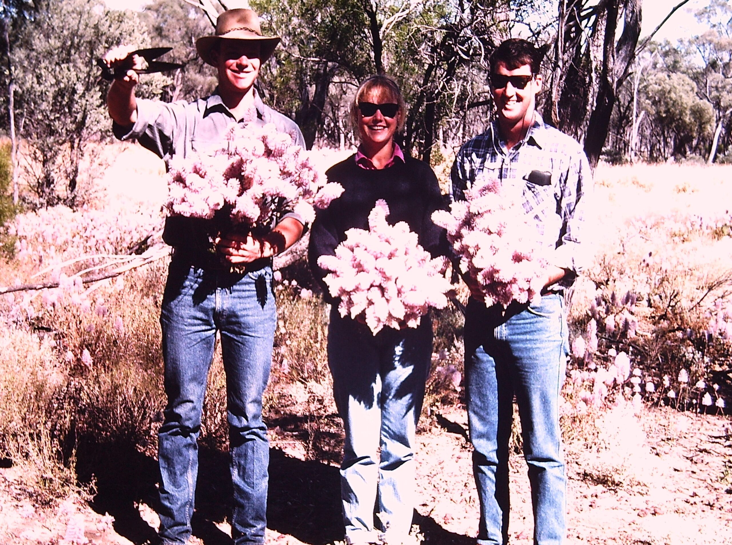 Three people holding bouquets of native flowers.