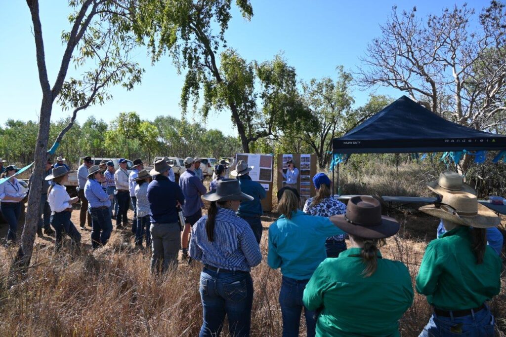 A photo of forum participants standing in the paddock in front of tent and displays listening to a presentation by Robyn Cowley.