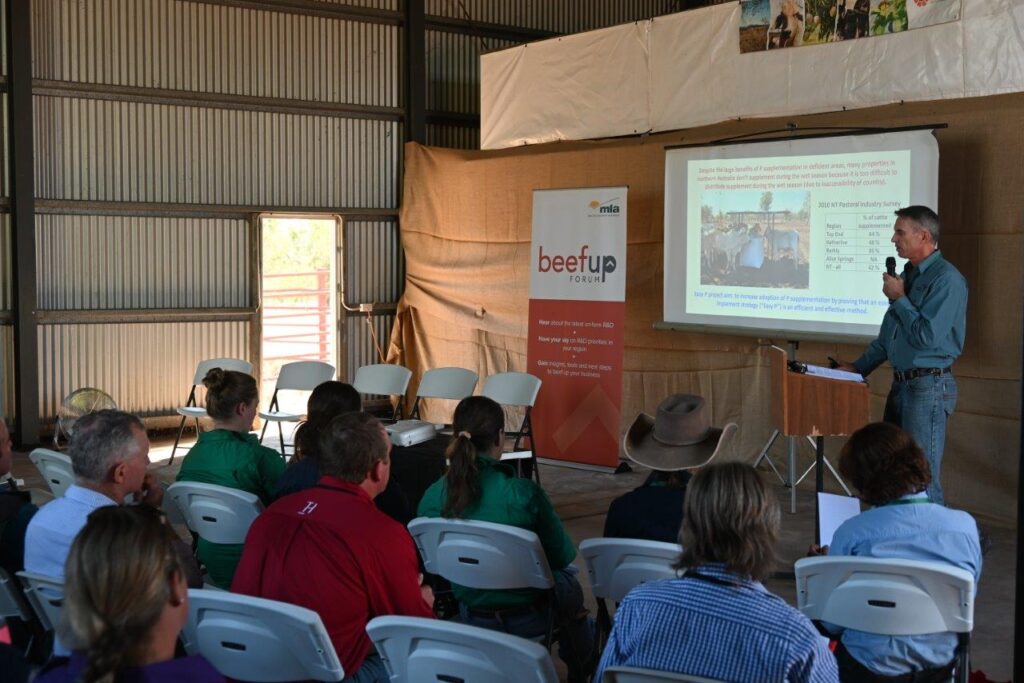 Photo of Tim Schatz giving his presentation to a group of forum participants seated inside a shed.