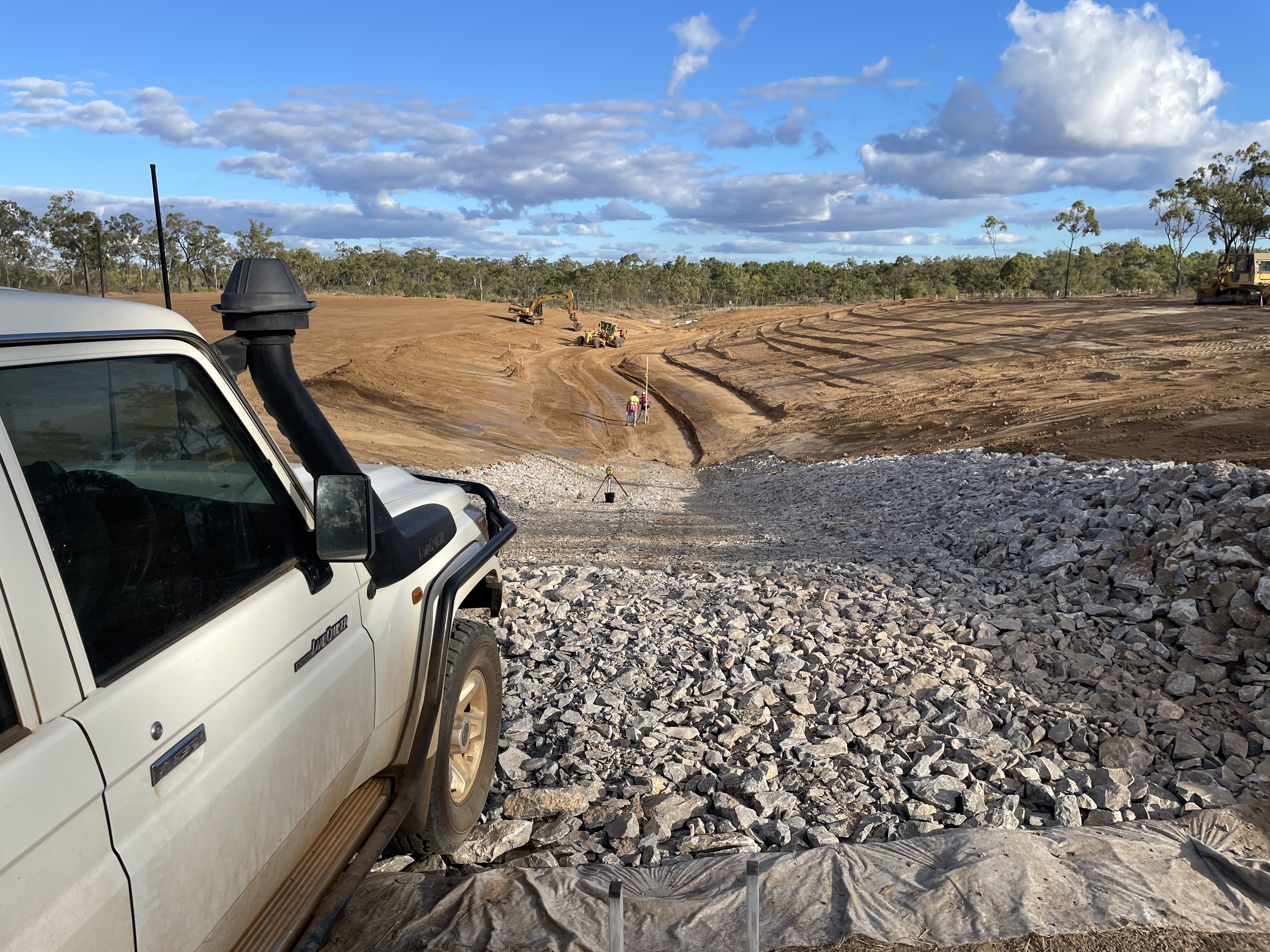 A 4 wheel drive parked on rocks in the foreground, substantial earthworks being conducted in the background at a gully erosion site on Spyglass Research Facility.