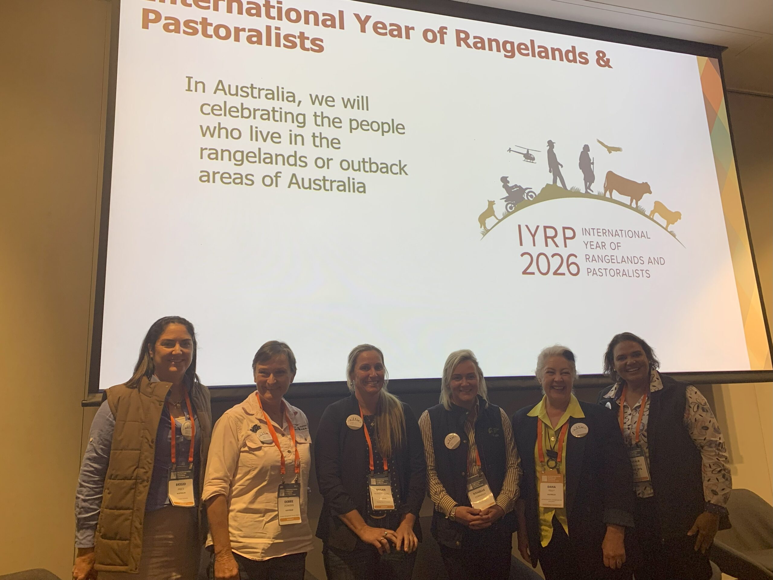 Group of six female producers standing in front of a slide promoting the 2026 International Year of Rangelands and Pastoralists