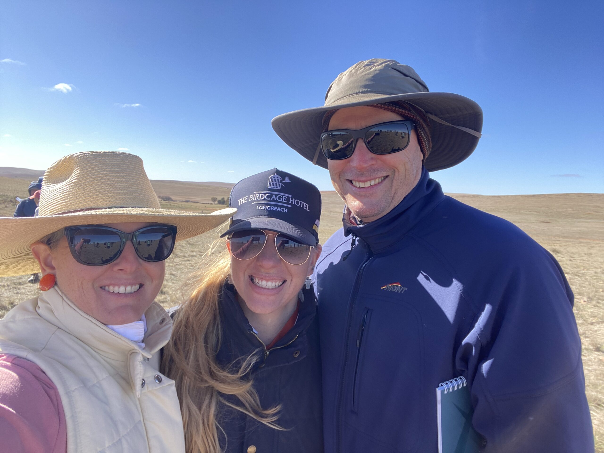Two women and a man huddled together taking a selfie in the wind.