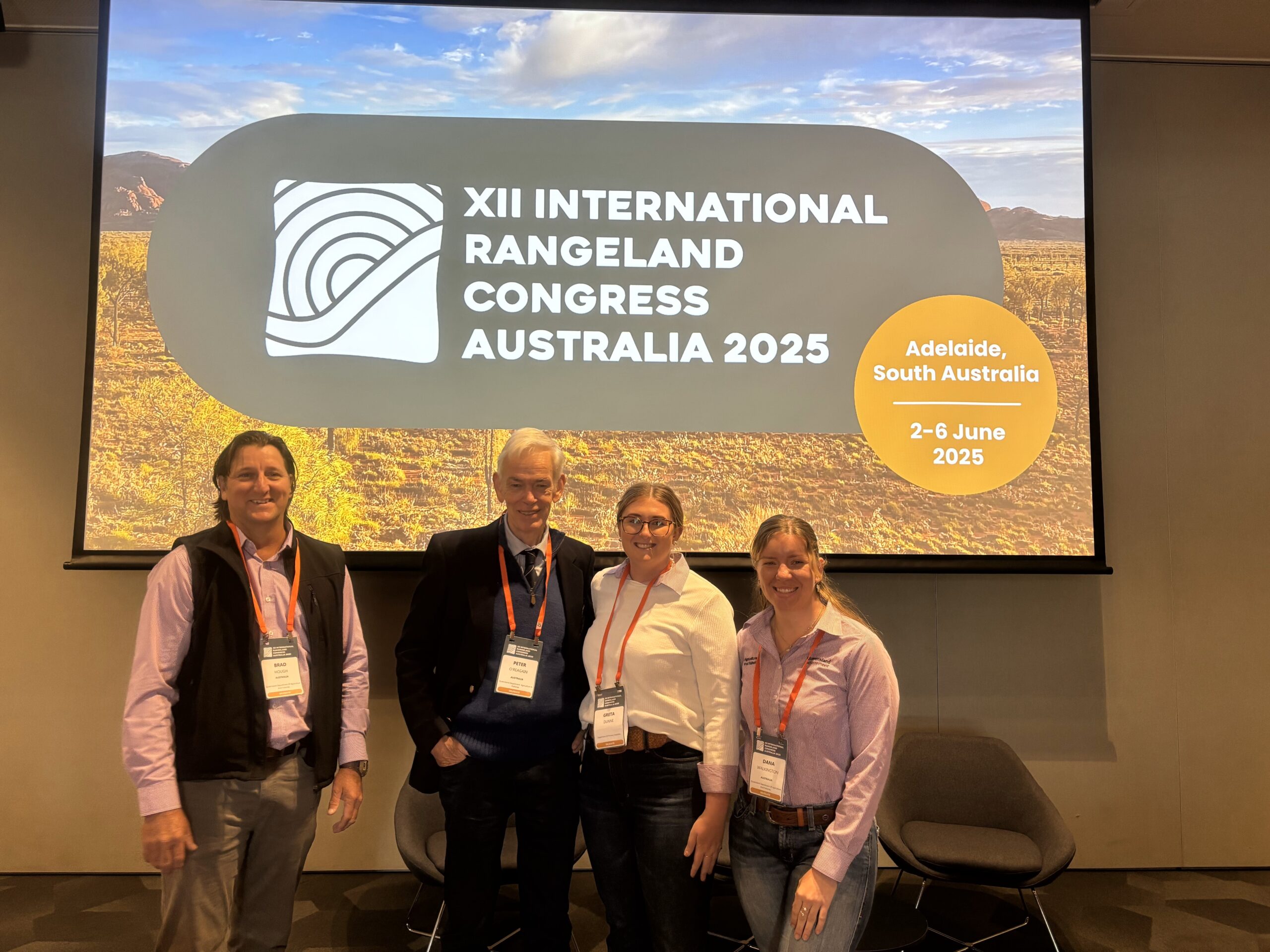 Two men and two women standing in front of a slide for the International Rangelands Congress 2025.