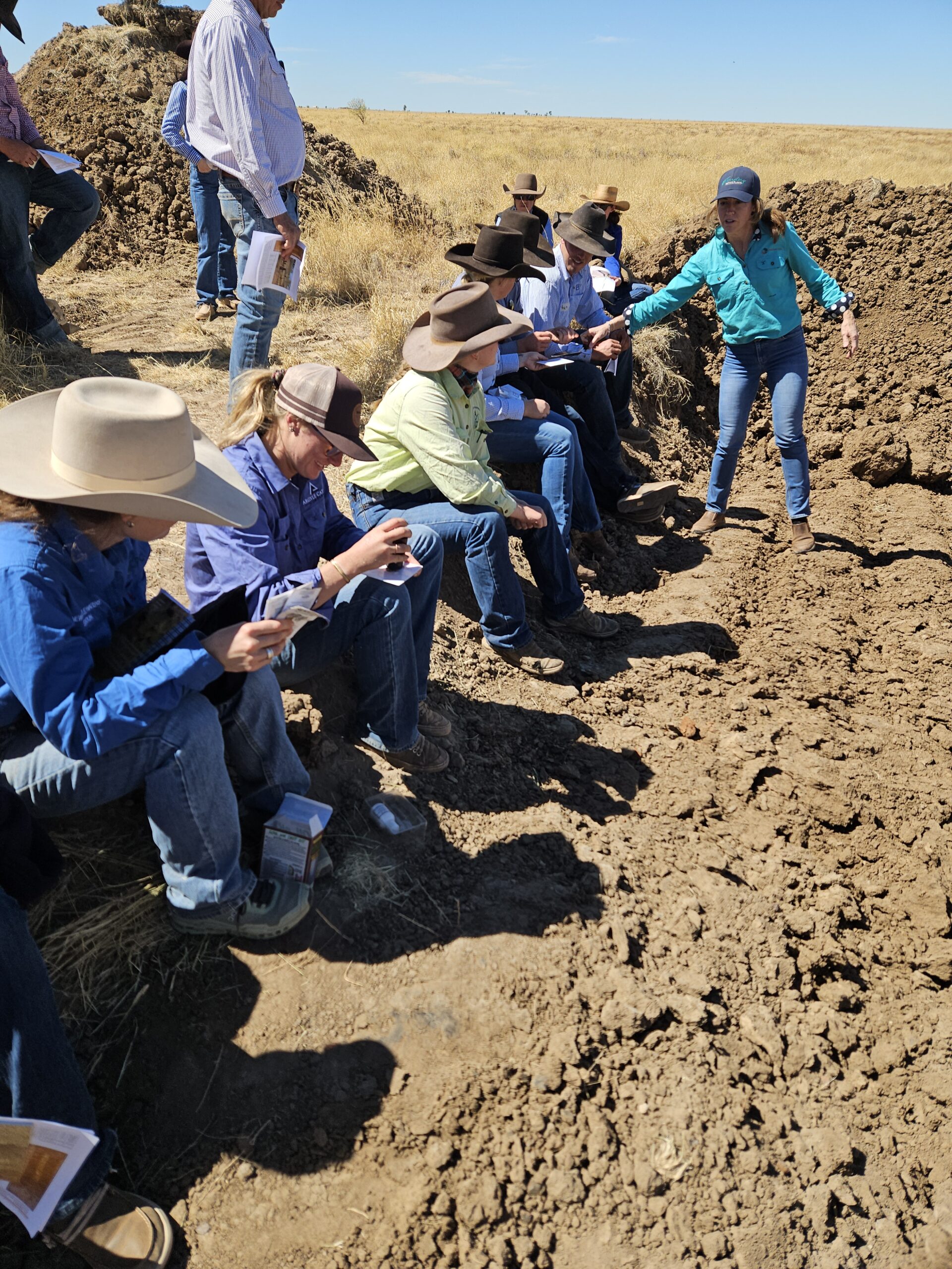 Barkly Herd Management Forum participants sit on the edge of a soil pit as they handle soil peds