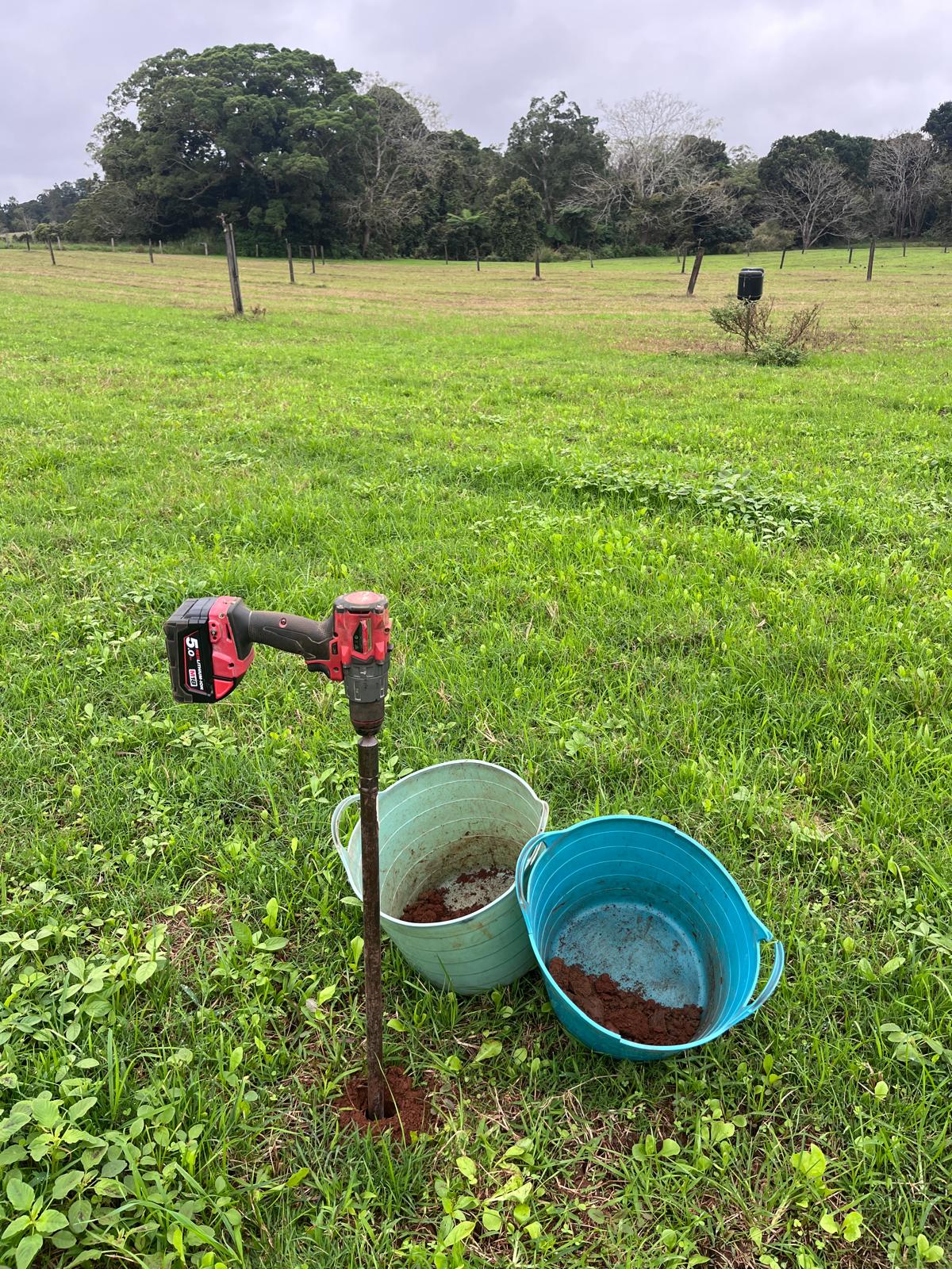 Soil corer attached to a drill with soil samples in buckets.