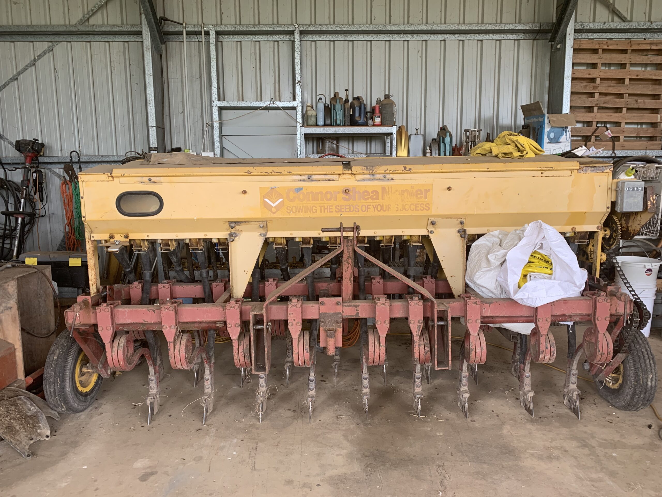 Yellow and red seed planter. Seed box on top with tines.