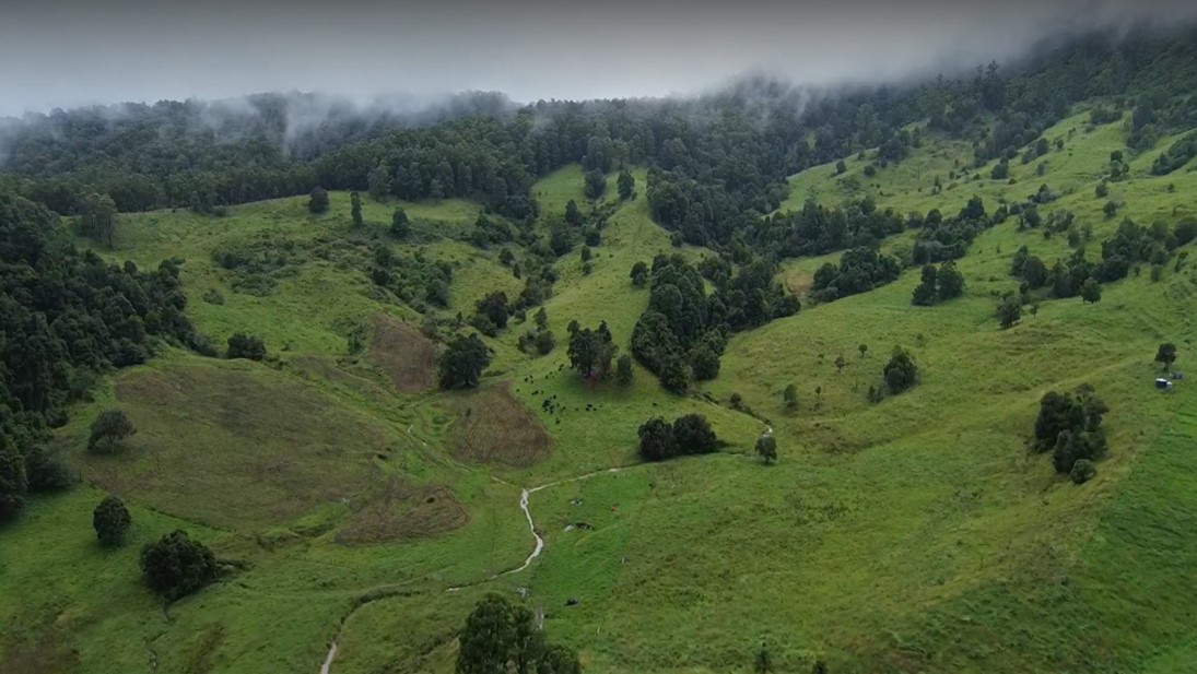 Drone photo of steep hilly country with green grass.