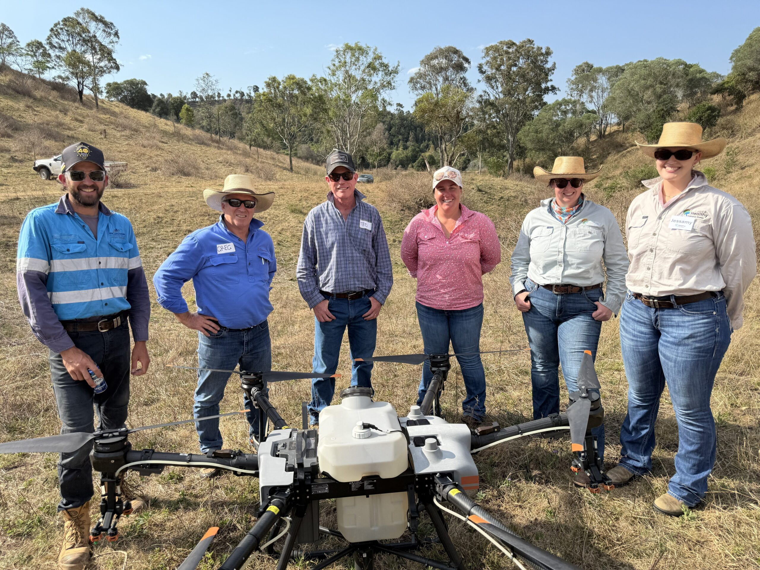 Group of people standing in front of a large agricultural drone.