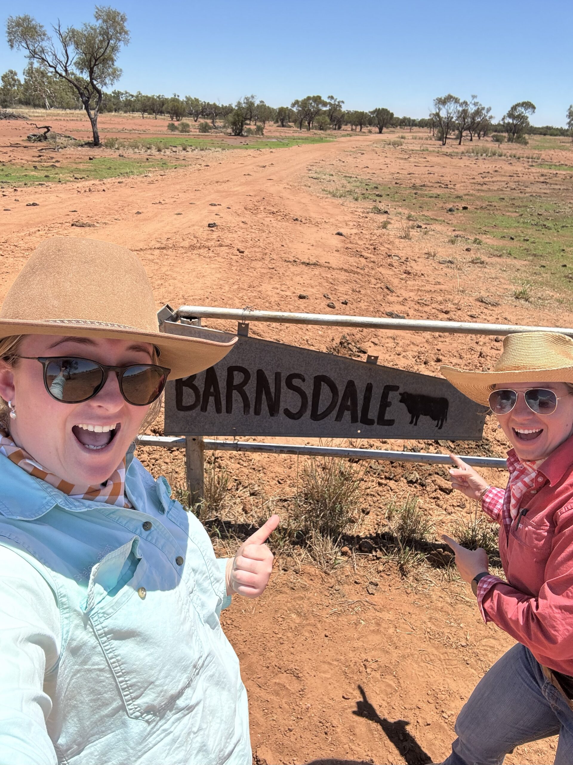 Two ladies wearing long sleeved shirts and big hats standing at a property sign that says Barnsdale.