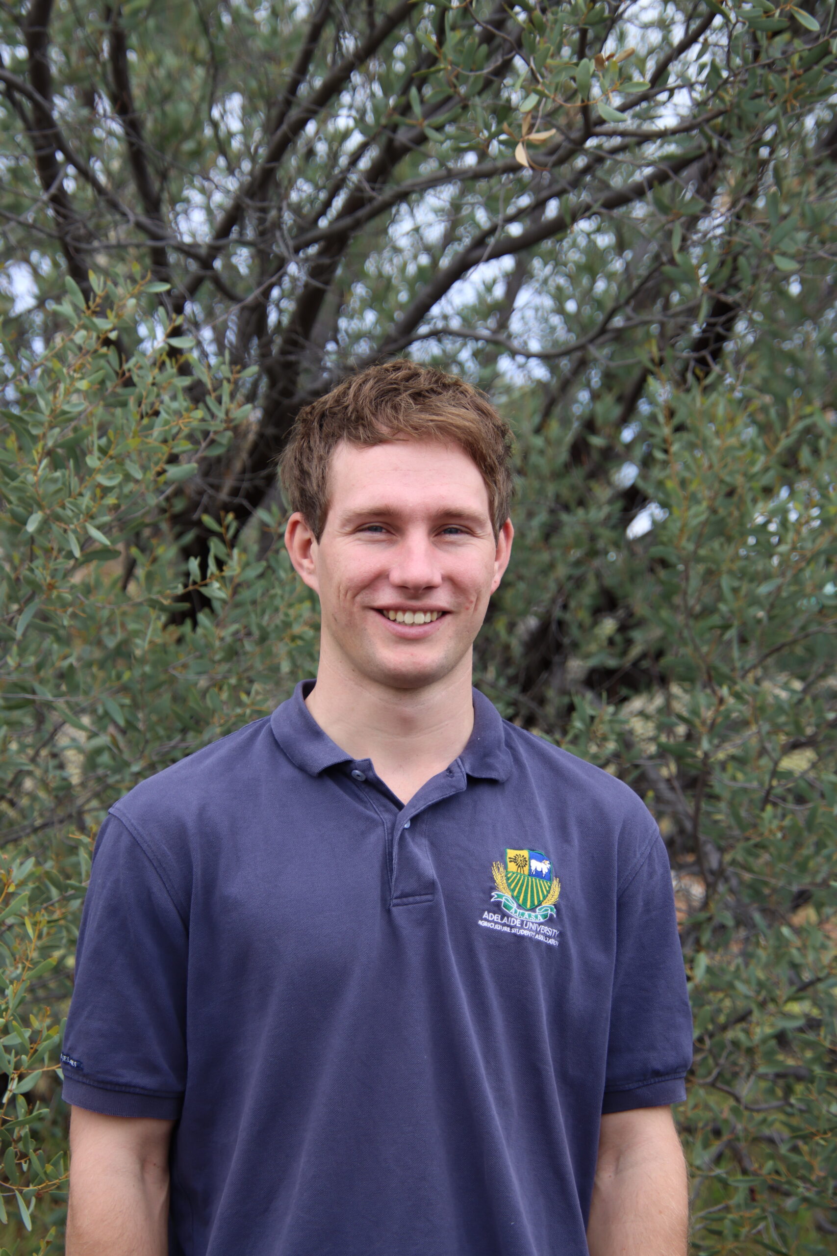 Livestock Extension Officer standing in front of trees