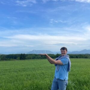 Beef extension officer standing in front of green pasture and mountain range