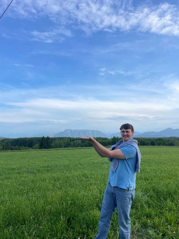 Beef extension officer standing in front of green pasture and mountain range