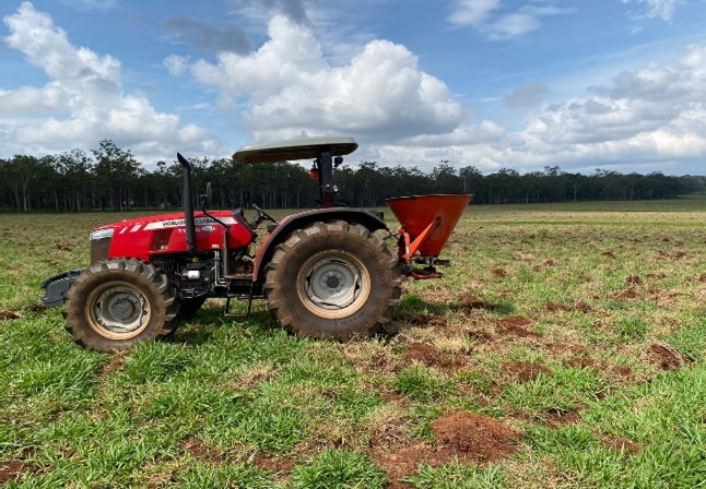 Red tractor with a fertilsier spreader on the back.