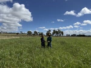 A man and a lady standing in a paddock of lush green grass.